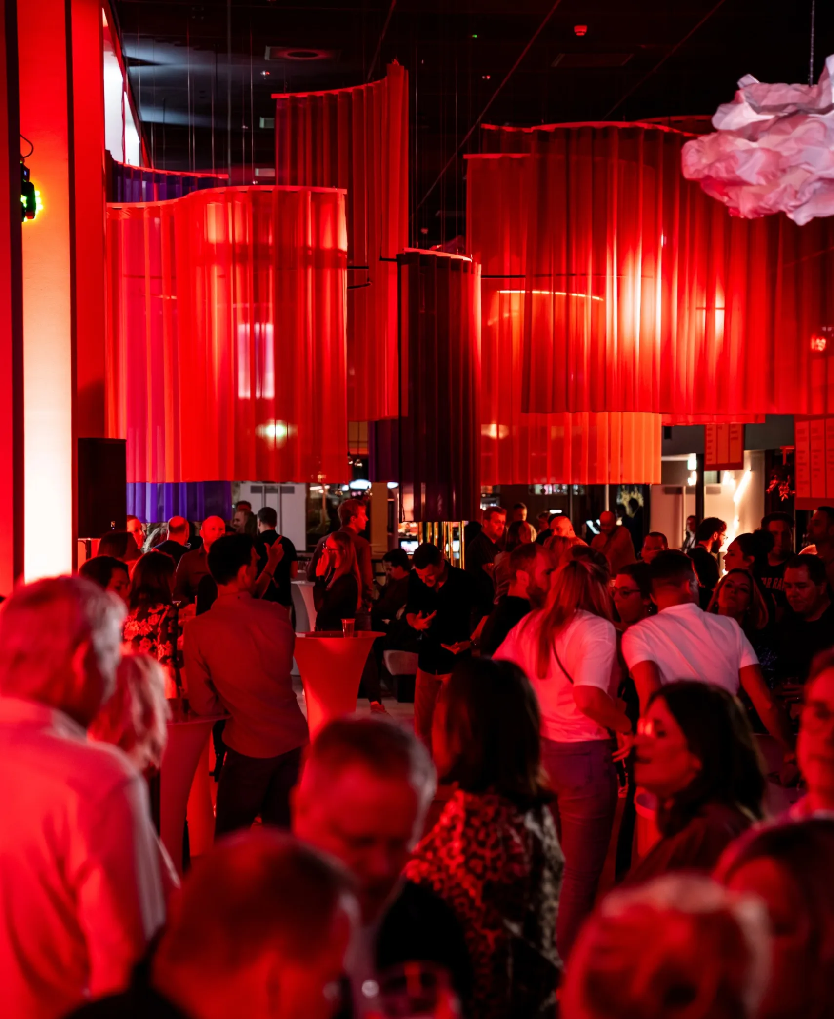 People at an event in a room lit up in red.
